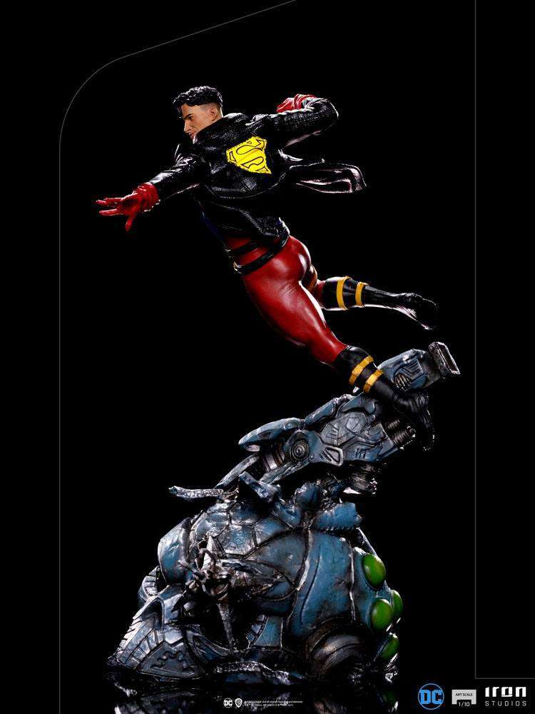 Side view of 28cm Iron Studios Superboy 1/10 scale statue in a black leather jacket, leaping over a metallic base.