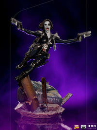 Iron Studios 1/10 scale Domino statue in a dynamic leaping pose with dual pistols against a purple background.