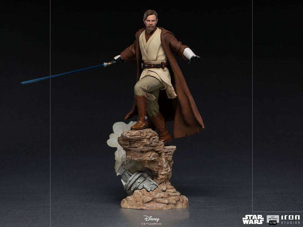 Iron Studios 1/10 Obi-Wan Kenobi statue in Jedi robes holding a blue lightsaber, standing on a rocky terrain base.