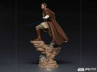 Side view of Iron Studios Obi-Wan Kenobi 1/10 scale statue in brown robes with a blue lightsaber on a rocky base.