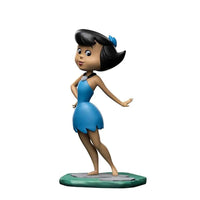 Iron Studios 14 cm Betty Rubble Art Scale statue in a blue dress, standing on a stone-textured base, side view.