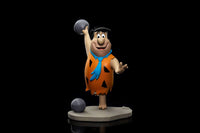 Iron Studios 1/10 scale Fred Flintstone statue in a bowling pose, wearing his signature orange tunic on a grey base.